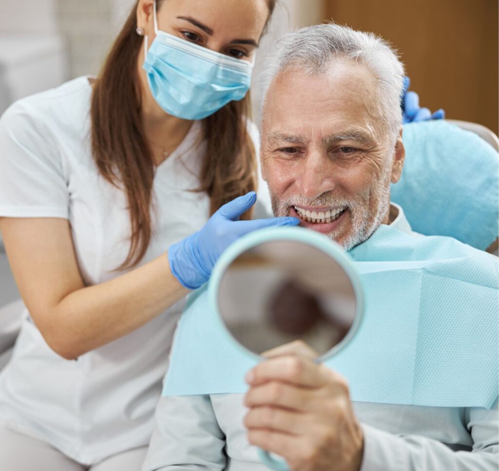Homem com uma dentista do lado sorrindo mostrando os deus dentes